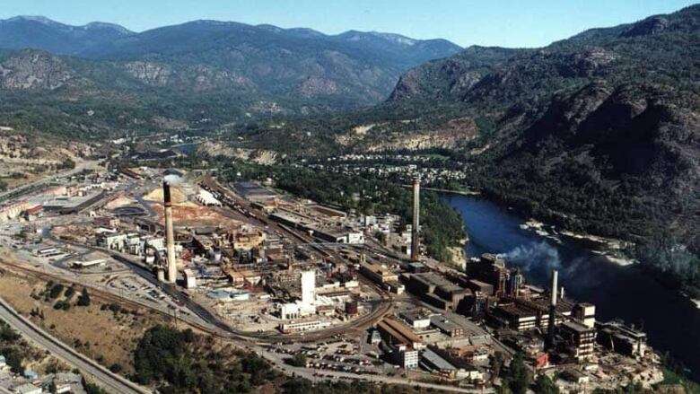 An aerial shot of a mining company's operations framed by mountains and flanked on the right by a river.