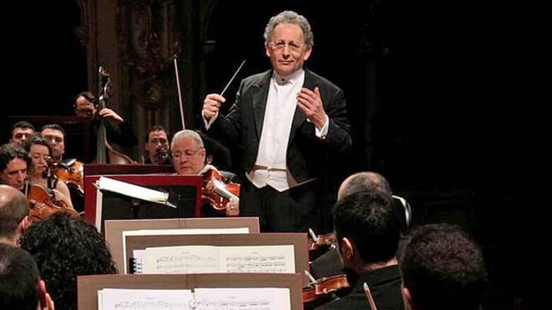 Boris Brott is seen in a tuxedo conducting an orchestra