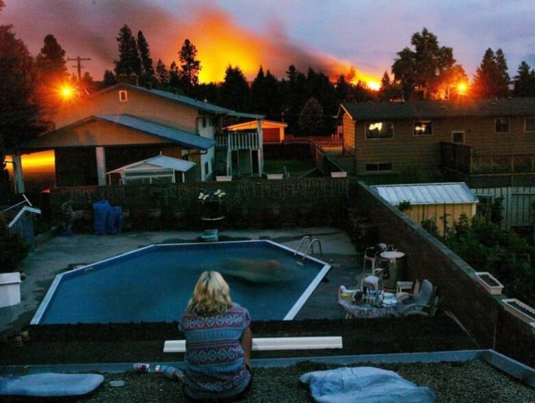 A resident watches as flames behind a number of houses approach.