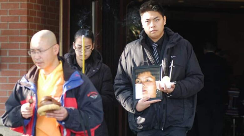 Jennifer Pan is shown carrying incense at her mother's funeral earlier in November. Her brother is pictured on her right.