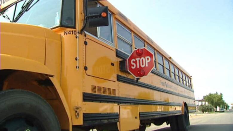 A close-up of the side of a school bus with its stop sign extended from the side of the bus.