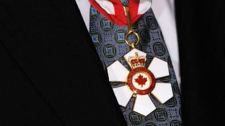 A close-up of an ornate medal hanging from a red ribbon, with the words Desiderantes Meliorem Patriem, Latin for 'they desire a better country.'