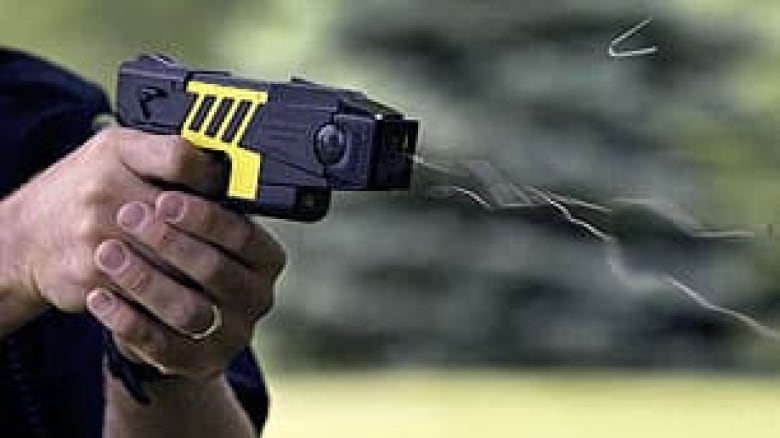 A hand holds a Taser gun as it's being fired. 