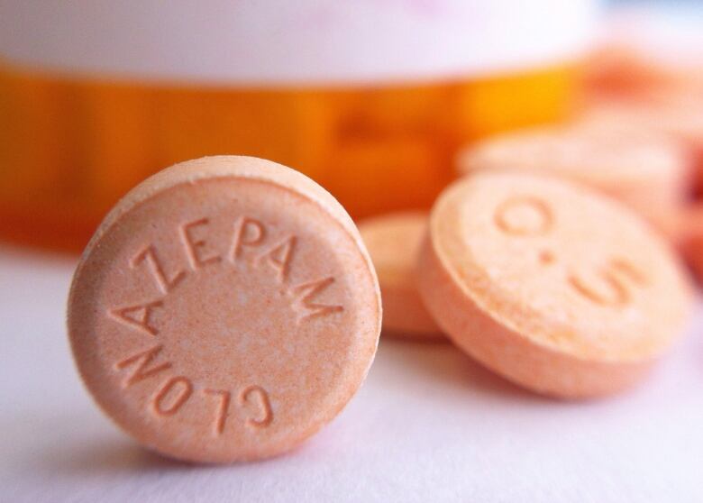 Orange pills marked 'Clonazepam' and '0.5', meant to represent generic drugs.