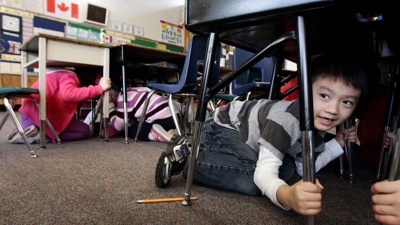 Schoolchildren hide under classroom desks during an earthquake drill