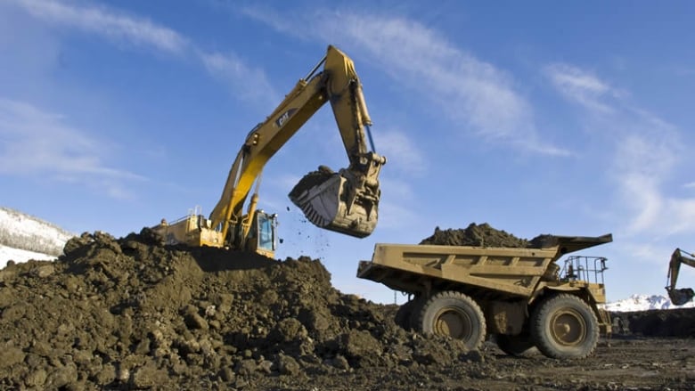 Heavy machinery are seen loading rock into a truck at a mine site.