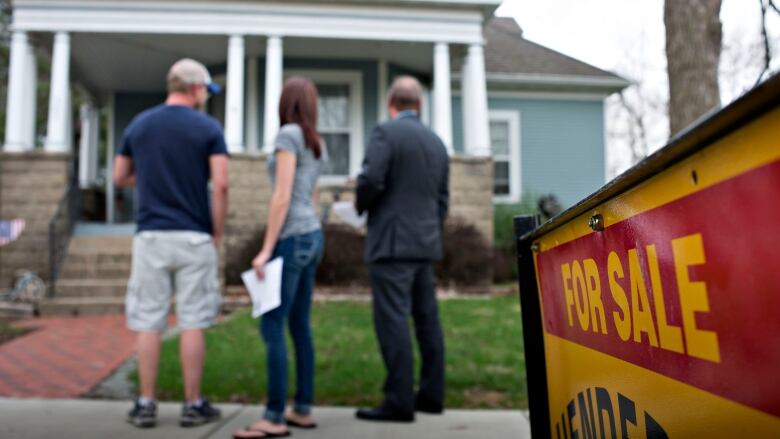 Three people look at a home for sale.