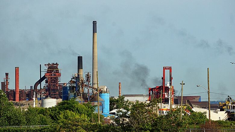 A view of smokestacks and machinery with black emissions in the air above.