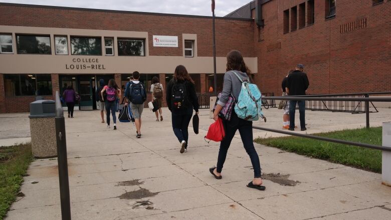 Students walk into a school. 