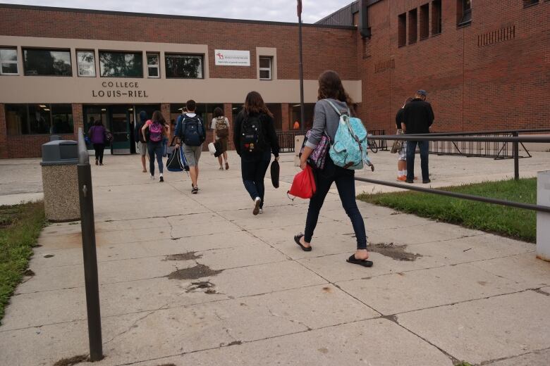 Students walk into a school. 