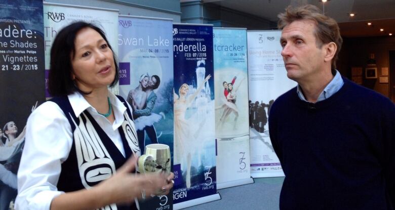 A woman and man stand in front of promotional ballet posters.