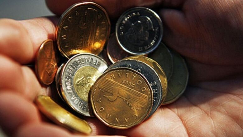 A pile of coins sits in a person's hand.