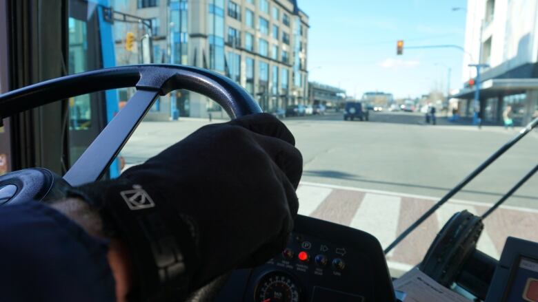 A hand in a black glove on a steering wheel. 