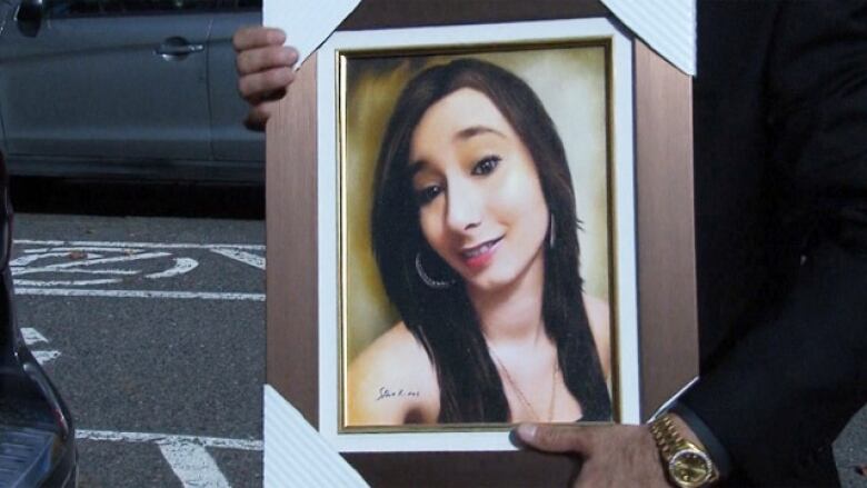 someone holding a framed portrait of a young brunette