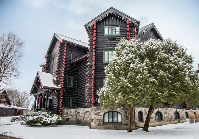 A large dark-coloured log building covered in snow.