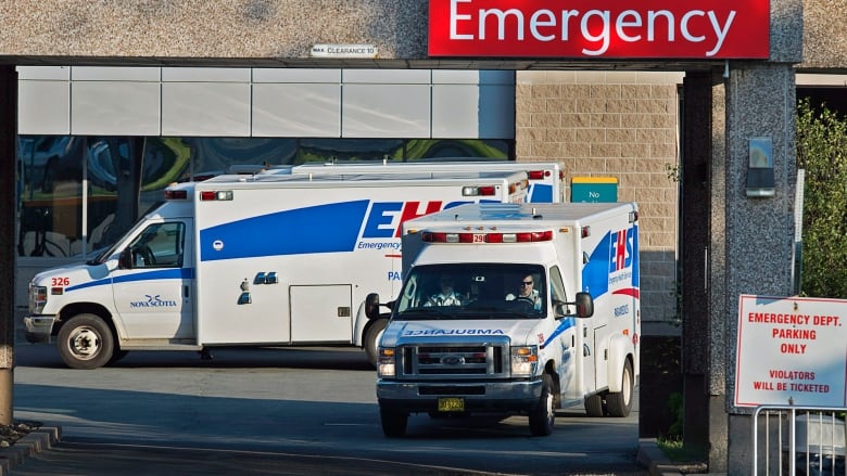 Two ambulances wait outside a hospital emergency department.