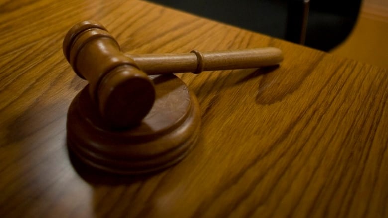 A closeup shows a wooden gavel on a desk.