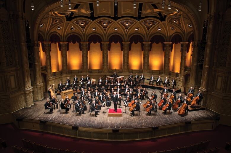 An orchestra conductor surrounded by performers in Vancouver Orchestra's building.