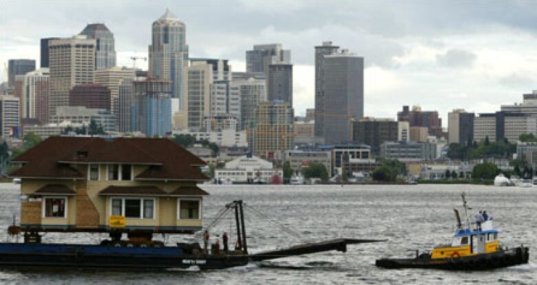 A large home is seen being towed away in a barge.