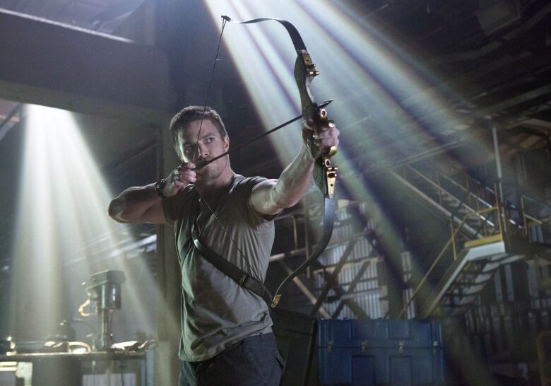 An actor poses with a bow and arrow.