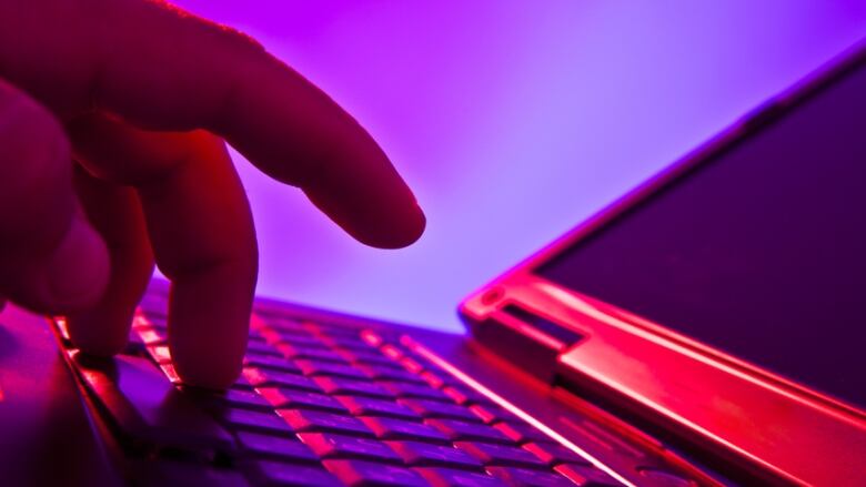 A closeup of fingers typing on the keyboard of a laptop computer.