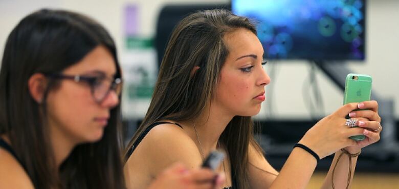 Two girls on their phones.