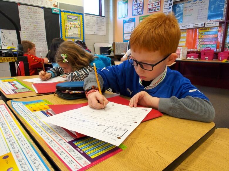 An elementary aged student does work at a desk