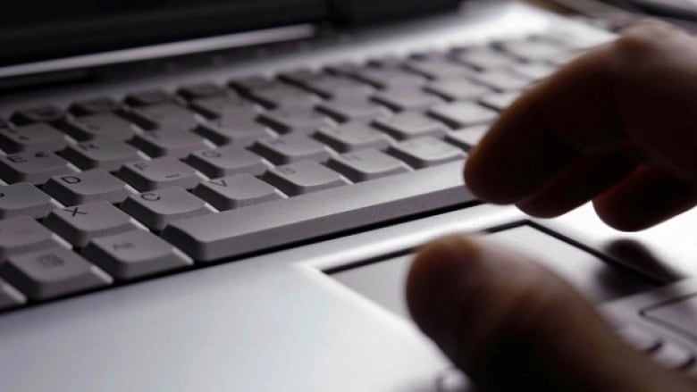 a hand hovers over a computer keyboard