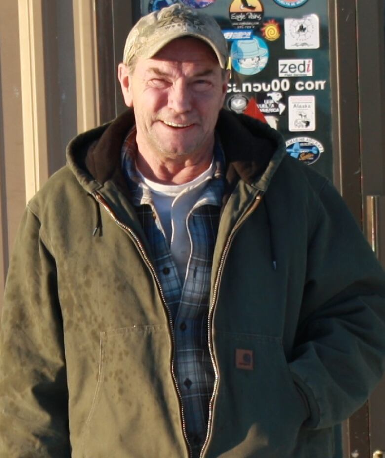 A man in a cap stands outside a building.