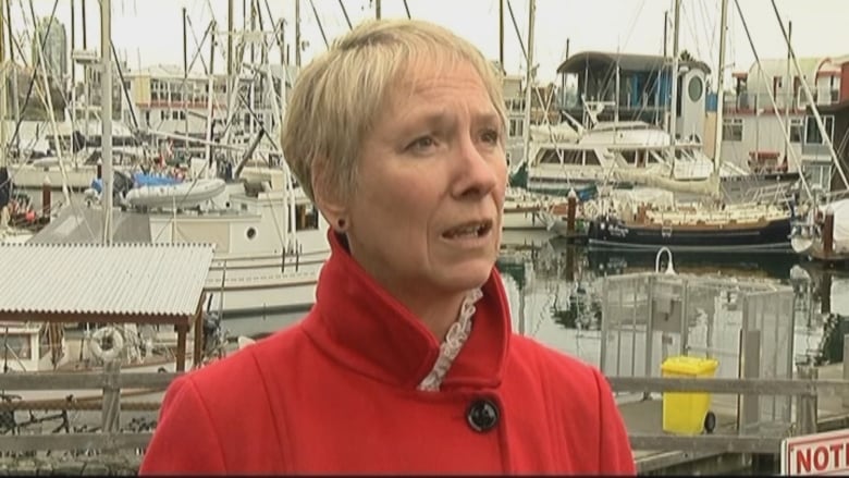 Barb Desjardins speaks in front of a marina with multiple boats behind her.