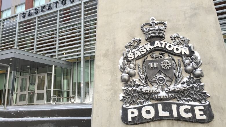 A cement block with Saskatoon police written on it is in the forefront and the saskatoon police station is in the background