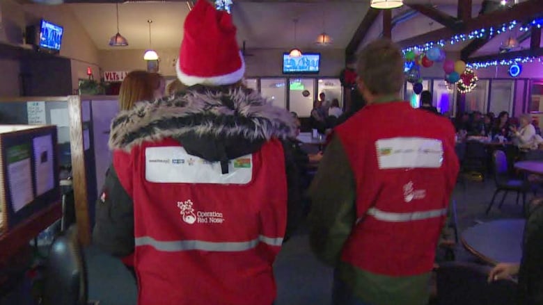 Two volunteers wearing red vests that say 