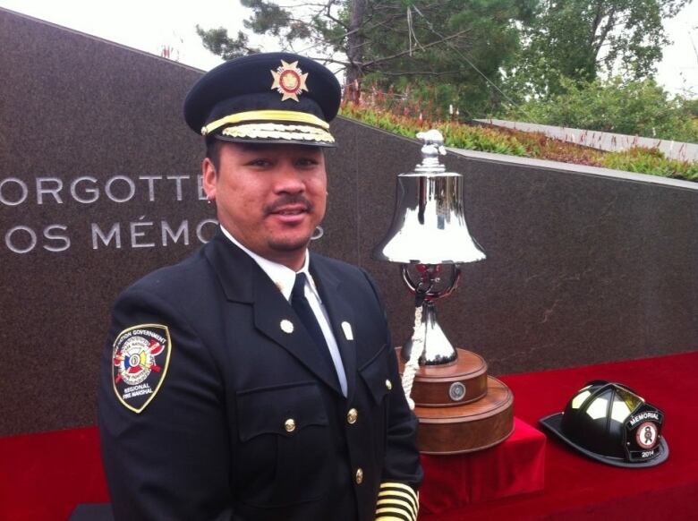 A Cree man in a uniform smiles at the camera