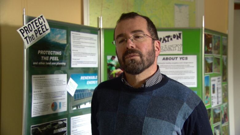 A white man stands in front of a poster board that reads 'Protect the Peel'