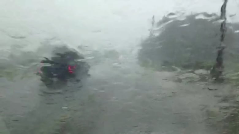 A vehicle is shown through a rainy window.