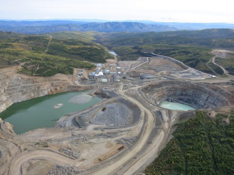 An aerial view of a mine, with tailings ponds, roads and buildings visible.