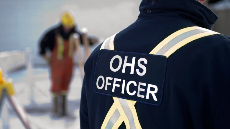 A OHS officer uniform is seen from behind.