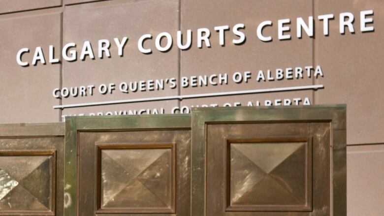 The entrance to the Calgary Courts Centre has the name on the side of the exterior wall, above four of the original brass doors that are displayed.