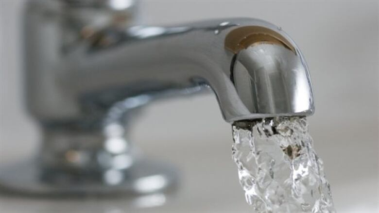 A close-up photo of a water tap with water flowing out of it.