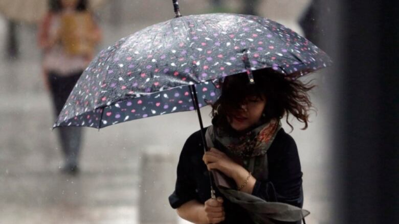 A woman holding an umbrella with her hair in her face.