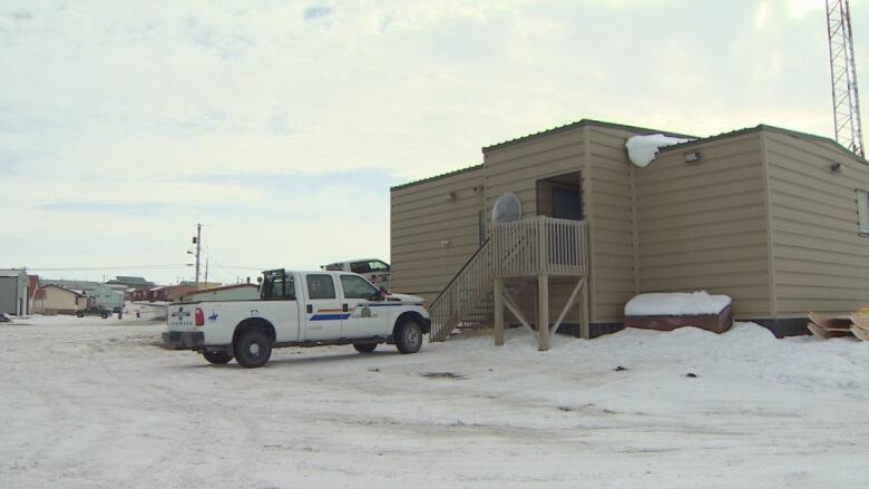 A small beige building with an RCMP truck parked in a snowy parking lot. 