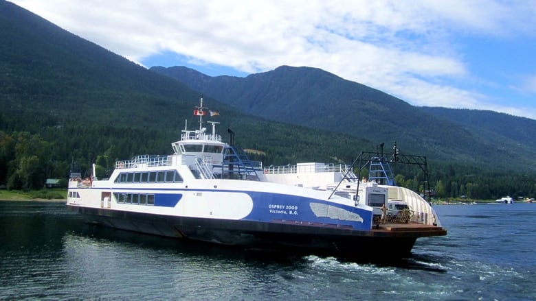 A large blue and white ferry plies mountain-ringed blue waters.