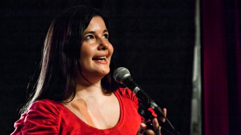 A woman looks upward while holding a microphone.