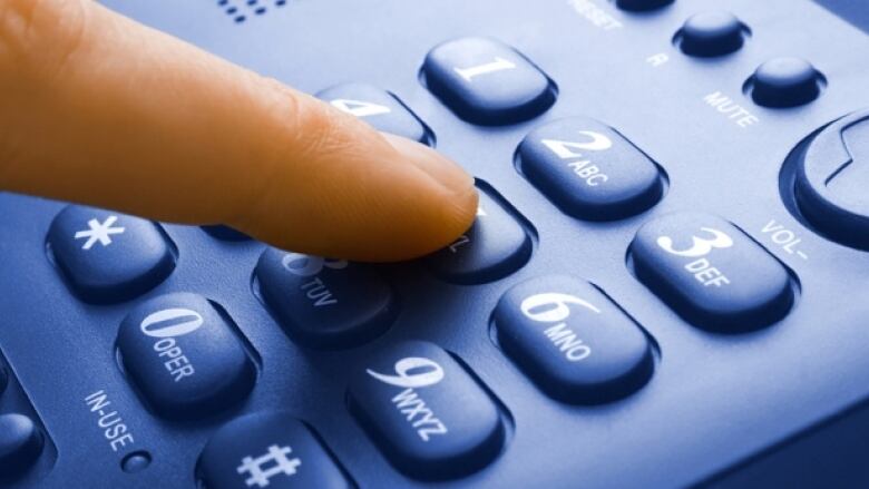 A finger is touching the keypad of a phone.