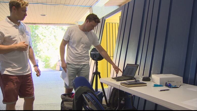 Researchers wearing sports gear point to a laptop in a lab.