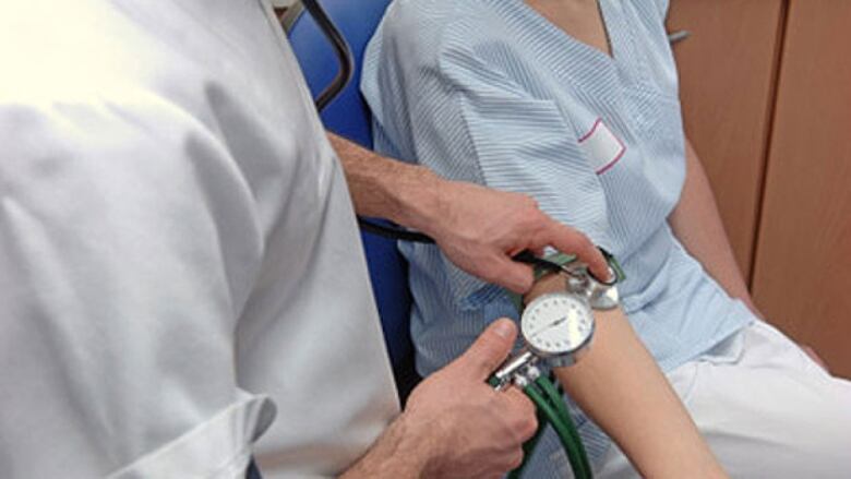 A health care professional takes a patient's blood pressure.