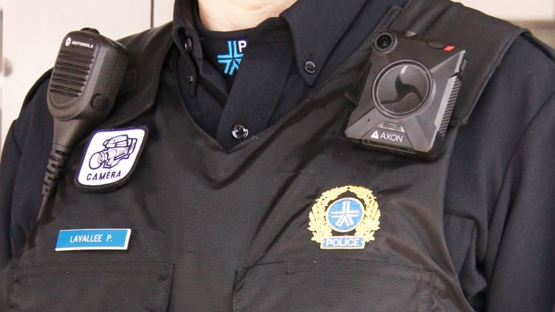 A person poses wearing a police body camera.