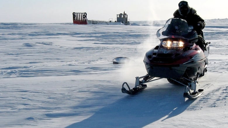 A man rides a snowmobile over icy terrain.