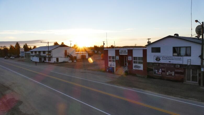 The sun rises over buildings on a street of a small town.