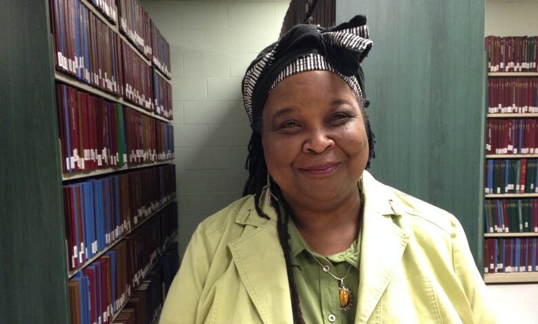 A Black woman in a library wearing a lime green jacket 